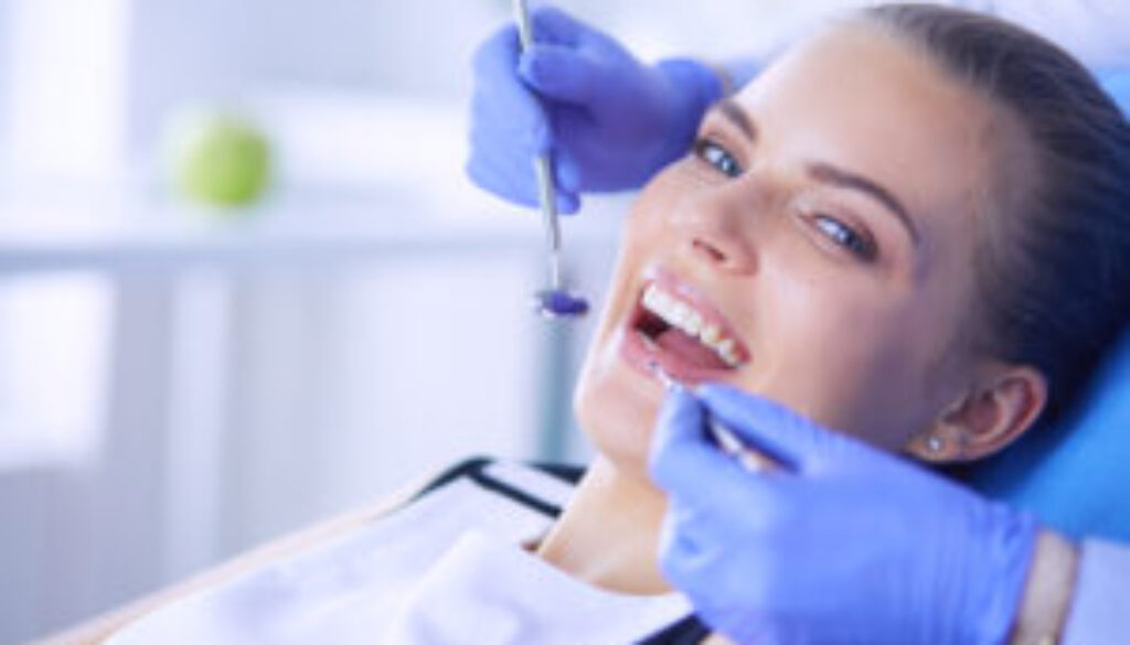 Young Female patient with open mouth examining dental inspection at dentist office.