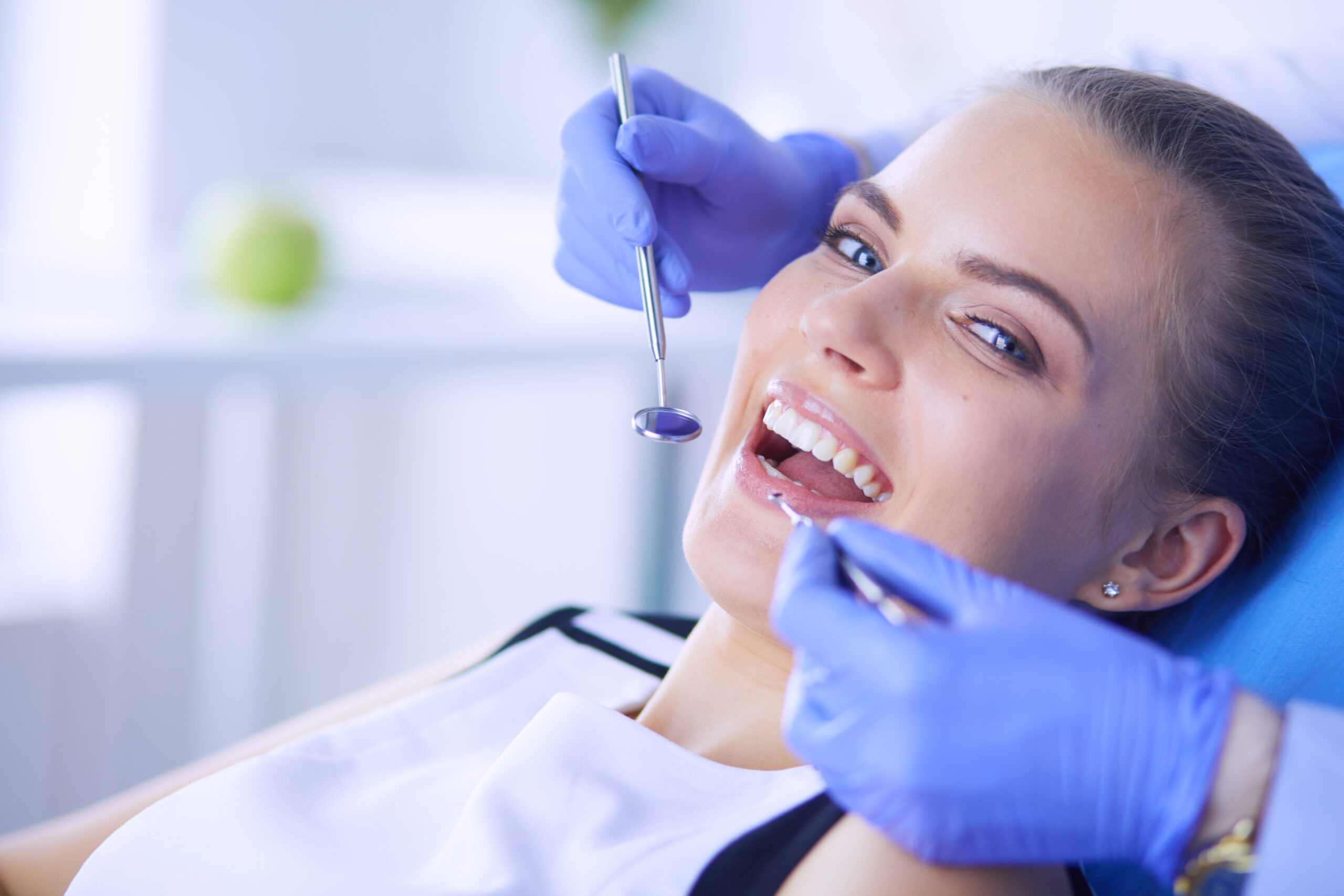 Young Female patient with open mouth examining dental inspection at dentist office.
